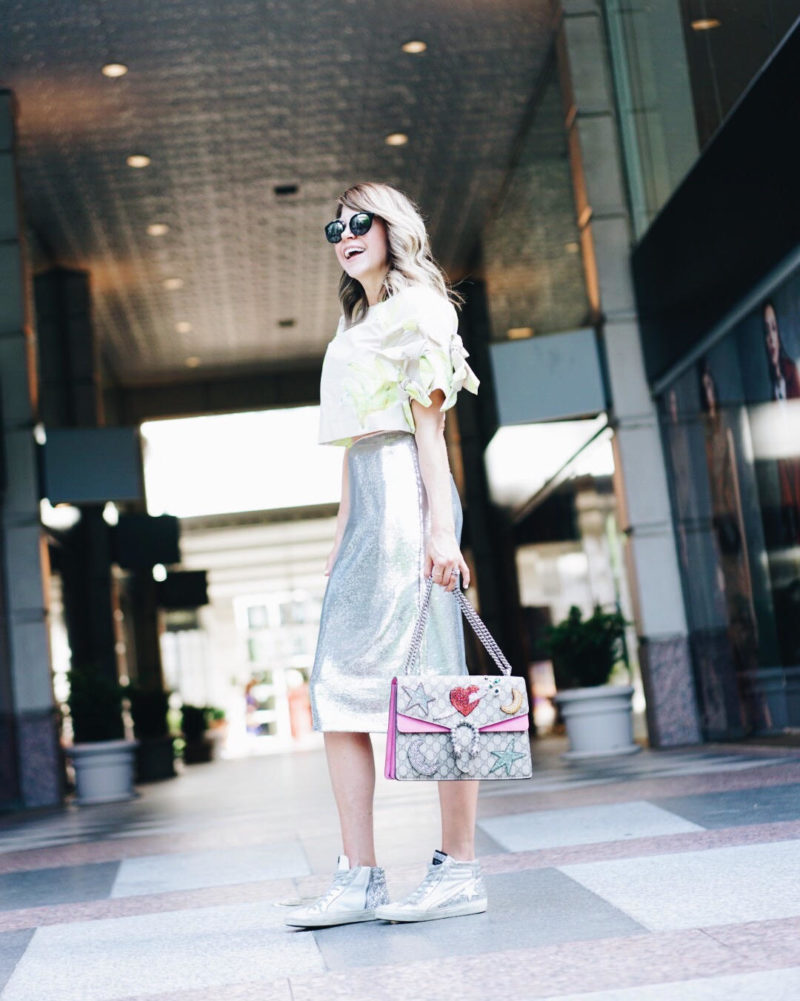 Diane Von Furstenberg sequin pencil skirt // Banana crop top shirt // Gucci Dionysus shoulder bag // Prada round aviator sunglasses // Blogger Lindsey Lutz styles her metallic, sequin pencil skirt with a gray MSGM banana crop top and Golden Goose sparkly high top sneakers at the Sole Society RewardStyle pool party in Dallas, TX